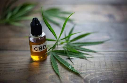 A bottle of CBD oil with a cannabis leave beside it.
