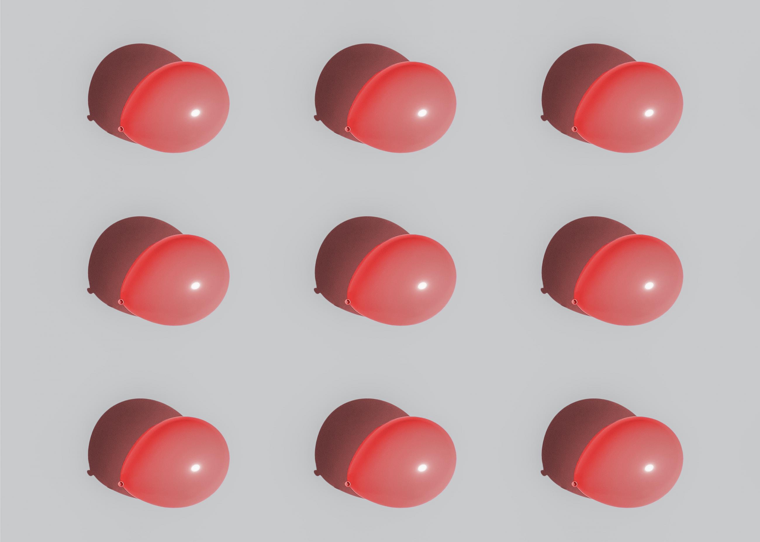Nine red blown up balloons aligned in rows of three against a white background